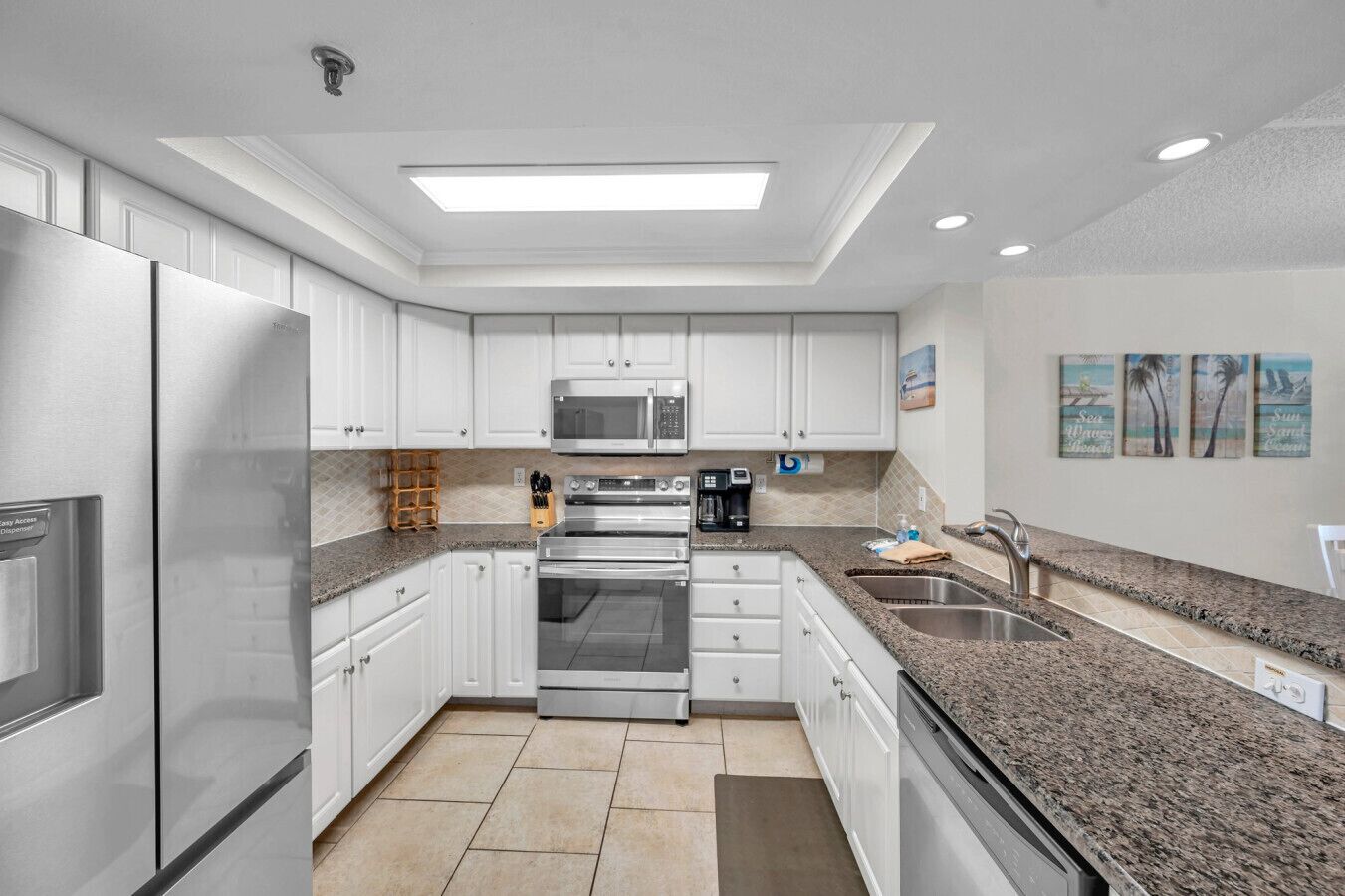 A modern kitchen with white cabinets, stainless steel appliances, granite countertops, and a central island.