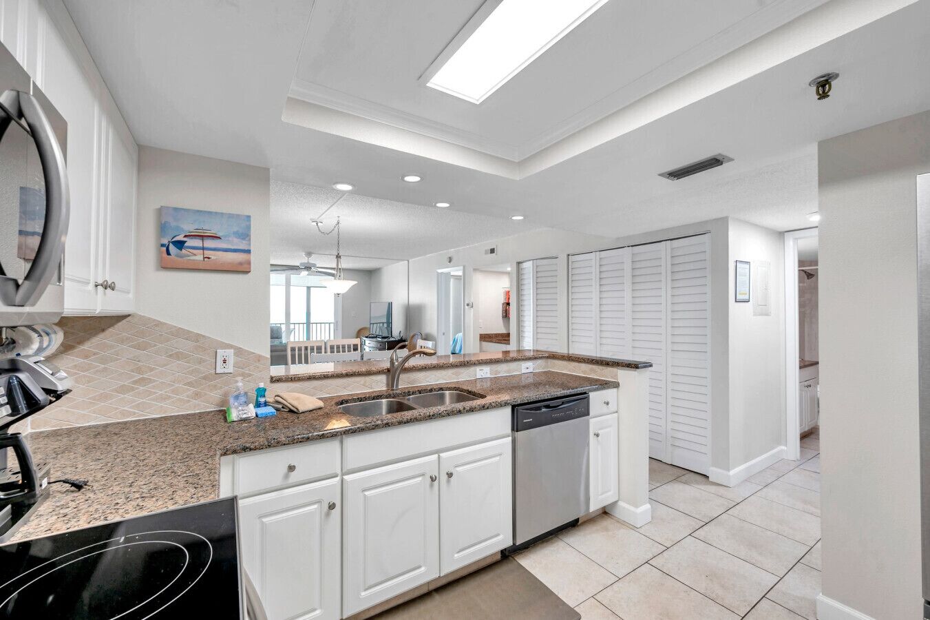 A modern kitchen with white cabinets, granite countertops, and a dishwasher.
