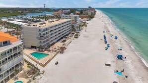 Un hotel frente a la playa con piscina, sombrillas y vista despejada al océano.