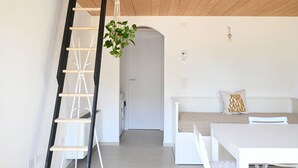 Ein Zimmer mit Holzboden, einer weißen Wand, einer weißen Tür, einer weißen Bank und einem weißen Tisch.
