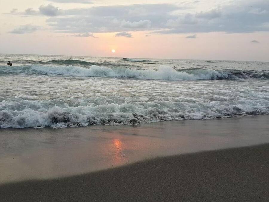 Una spiaggia con onde e un tramonto sullo sfondo.