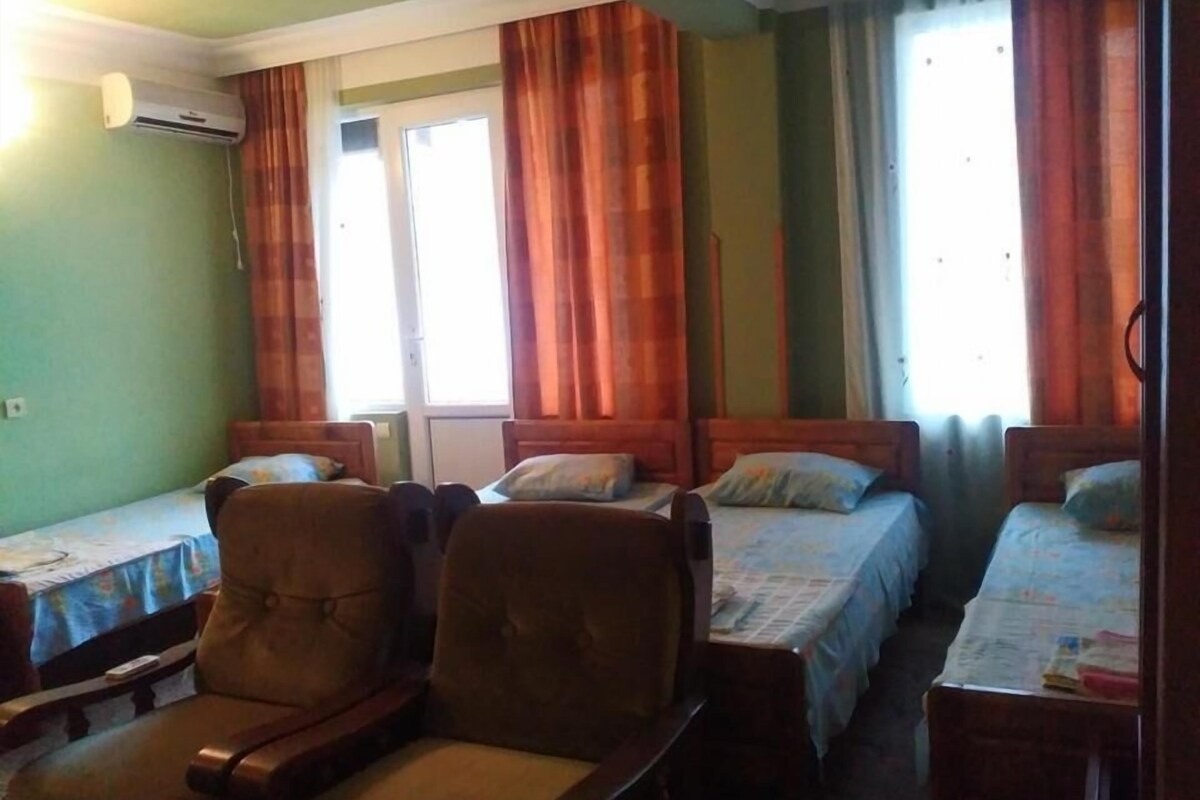 Una habitación con tres camas individuales, una silla de madera y un aire acondicionado.