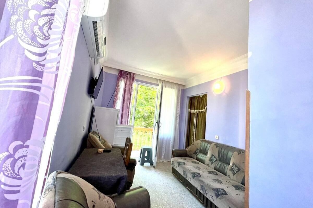 Una habitación con una cama, un sofá, una mesita y una ventana con cortinas.