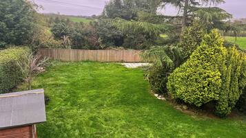 A well-maintained backyard with a wooden fence, a variety of shrubs, and a grassy lawn.