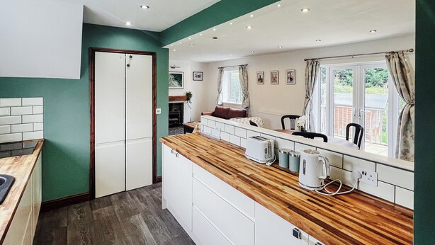 Una cocina moderna con armarios blancos, encimera de madera y una ventana con cortinas.