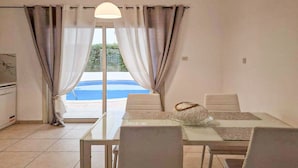 Zona pranzo con tavolo, sedie e vista su una piscina.
