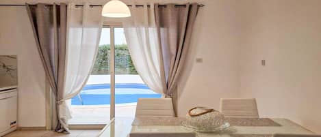 A dining area with a table, chairs, and a view of a swimming pool.