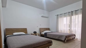 Una camera da letto con due letti, un comodino con una lampada e una finestra con tende.