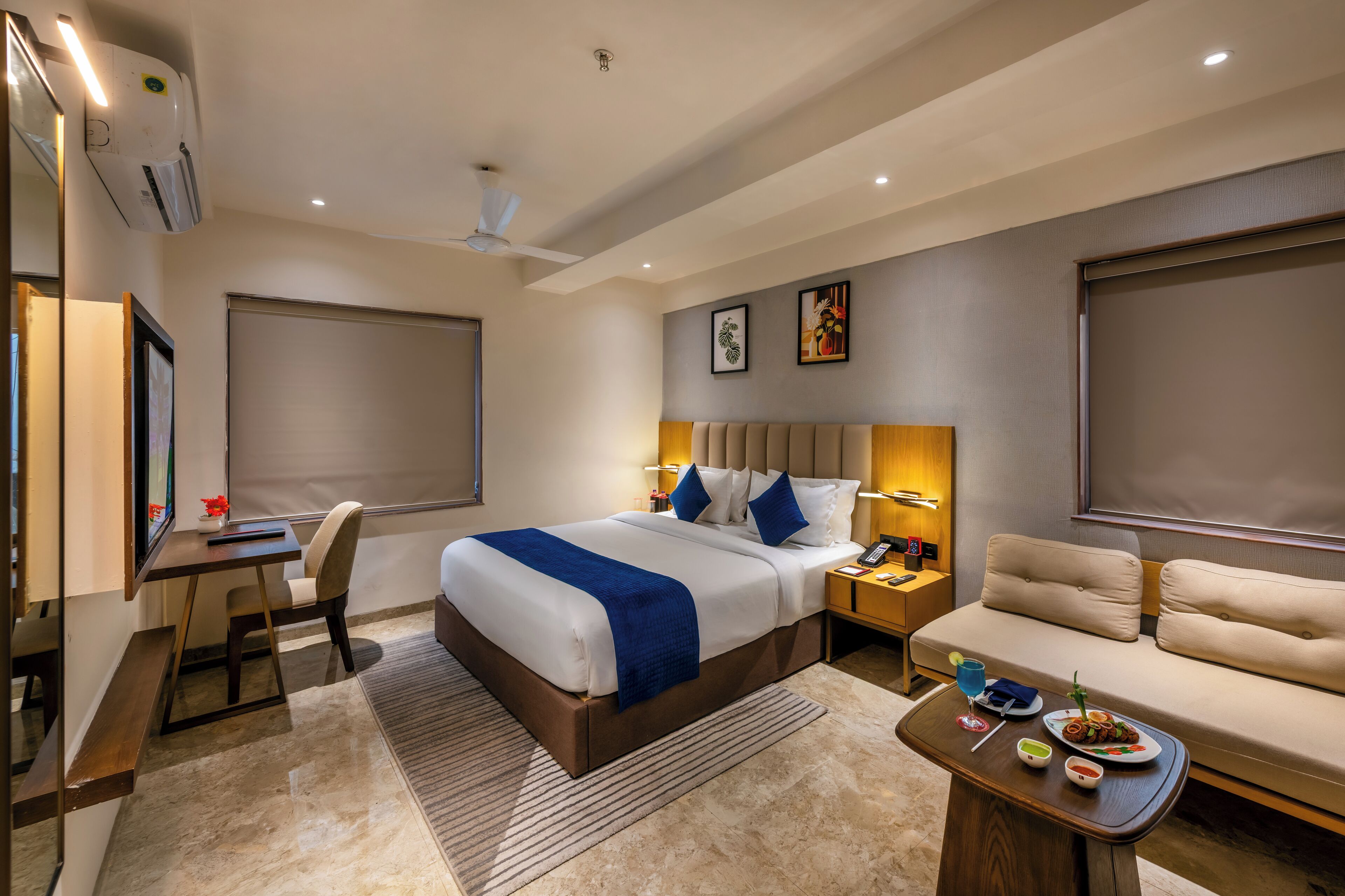 Een moderne hotelkamer met een bed, een bureau, een bank en een zithoek.