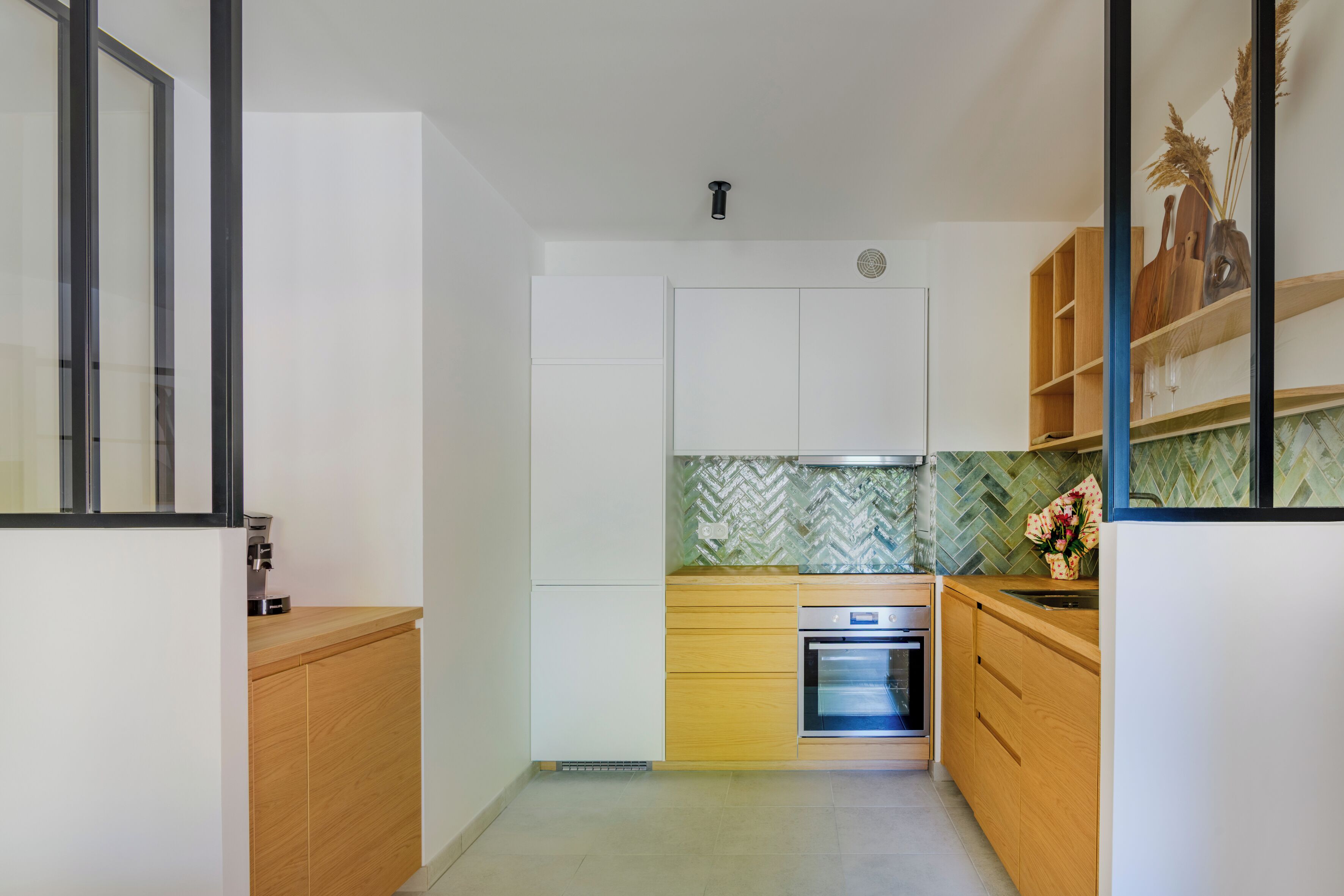 Une cuisine compacte avec des meubles en bois, un four encastré et un dosseret décoré d’un motif en chevrons.