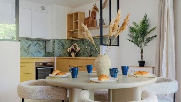 Een moderne keuken met een ronde eettafel, vier stoelen en een hanglamp.