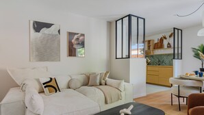 Een moderne woonkamer met een bank, een salontafel en een keuken op de achtergrond.
