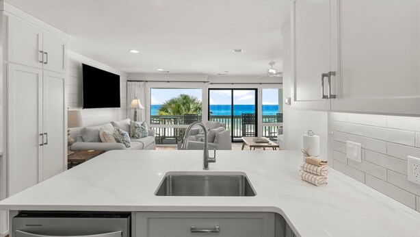 A modern kitchen with a large island, built-in appliances, and a view of the ocean.