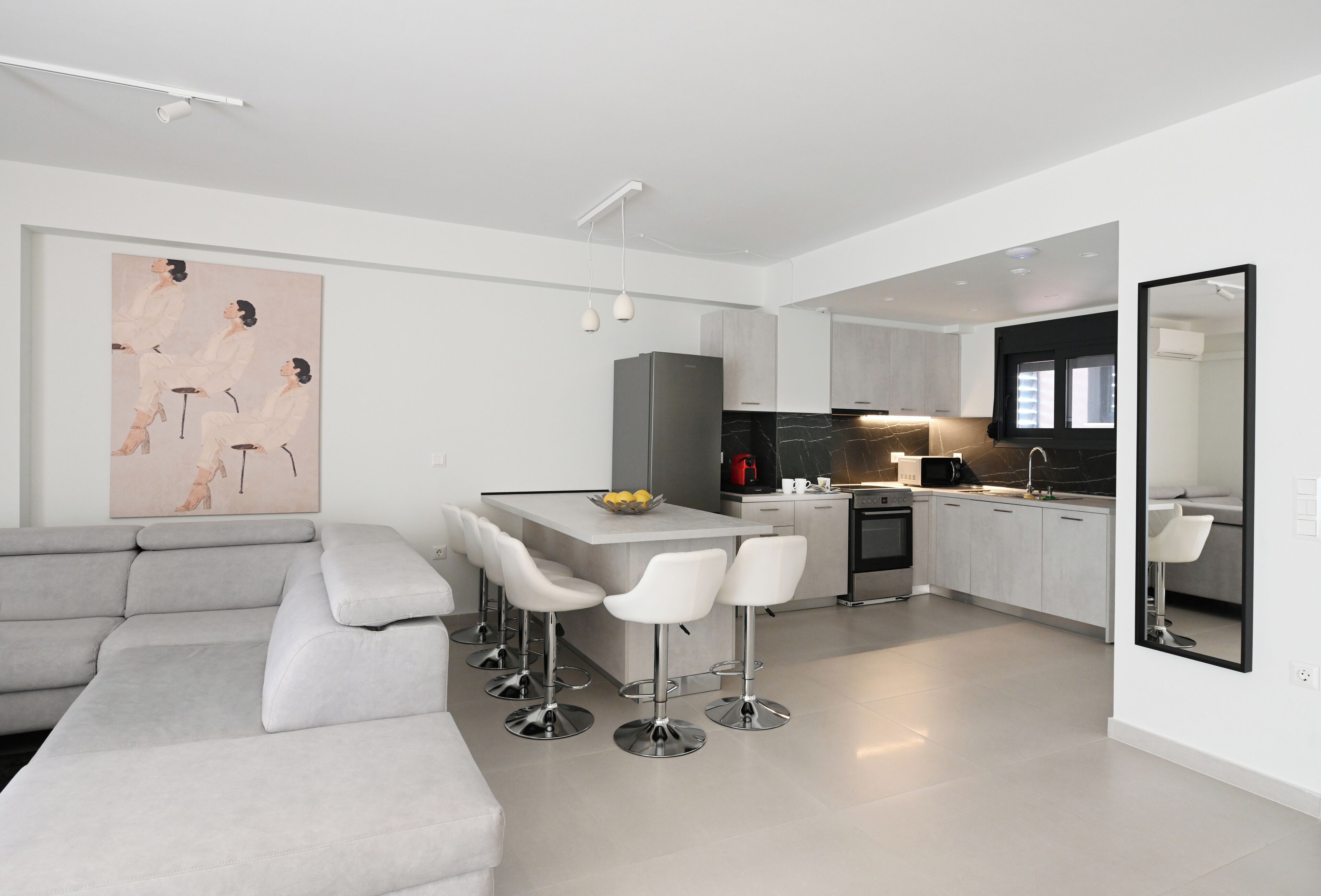 A modern kitchen with a central island, bar stools, and a large mirror.
