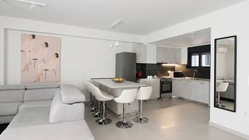 A modern kitchen with a central island, bar stools, and a large mirror.