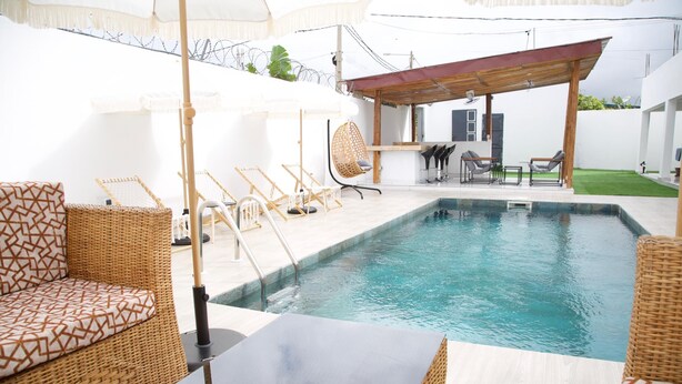 A swimming pool area with wicker furniture, a covered seating area, and a bar. - RESIDENCES CHELIEL, Morofé youth hostels (Yamoussoukro)