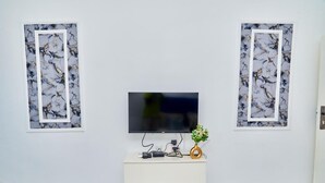 A flat-screen TV mounted on a wall with two framed artworks on either side. - RESIDENCES CHELIEL, Morofé youth hostels (Yamoussoukro)