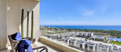 A balcony with a view of the sea and modern buildings.