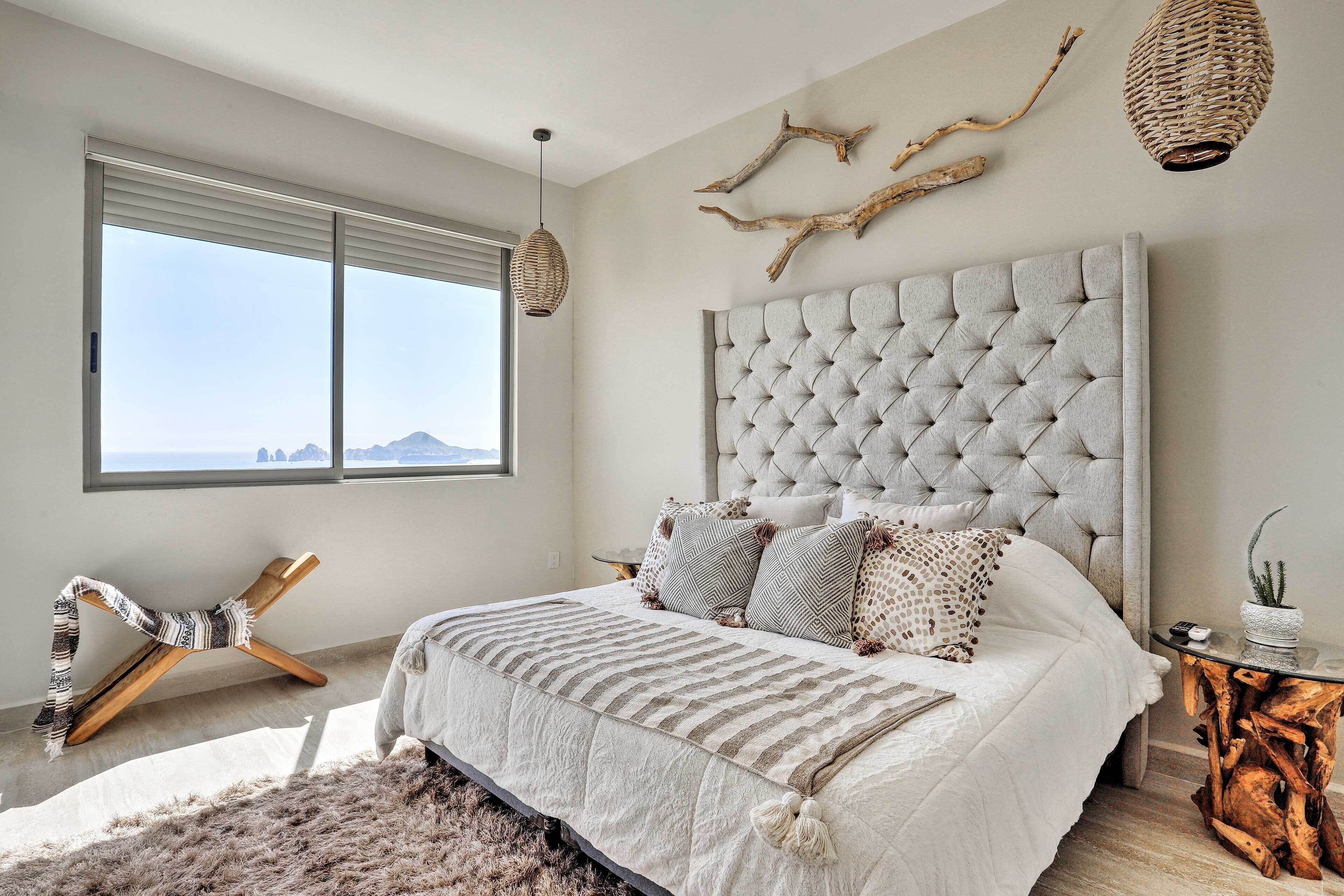 Une chambre dotée d’un grand lit, offrant une vue sur les montagnes, avec une chaise en bois et une table d’appoint en bois au design unique.