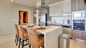 A modern kitchen with a central island, stainless steel appliances, and a dishwasher. - Luxe Cabo Condo w/ Ocean Views + Amenities! (Cabo San Lucas)