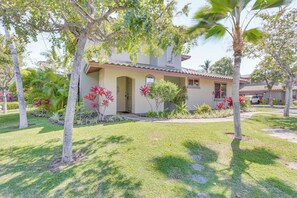 A house with a tiled roof, a front porch, and a well-maintained lawn with palm trees and tropical plants. - Private Beach Access: Kameula Townhome! (Kamuela)