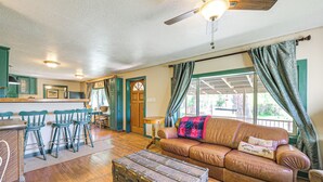 A cozy cabin interior with a wooden dining table, bar stools, a leather sofa, and a vintage trunk.