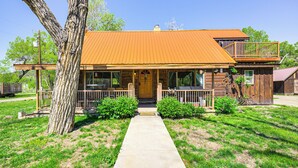 A two-story log cabin with a metal roof, a front porch, and a visible staircase leading to the upper level.