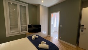 Une chambre d’hôtel équipée d’un lit, d’une télévision, d’une armoire et d’une porte donnant sur un balcon.