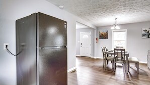 A kitchen with a stainless steel refrigerator, wooden dining table, and chairs. - 5 Mi to Dtwn: Family-friendly Fayetteville Home! (Fayetteville)