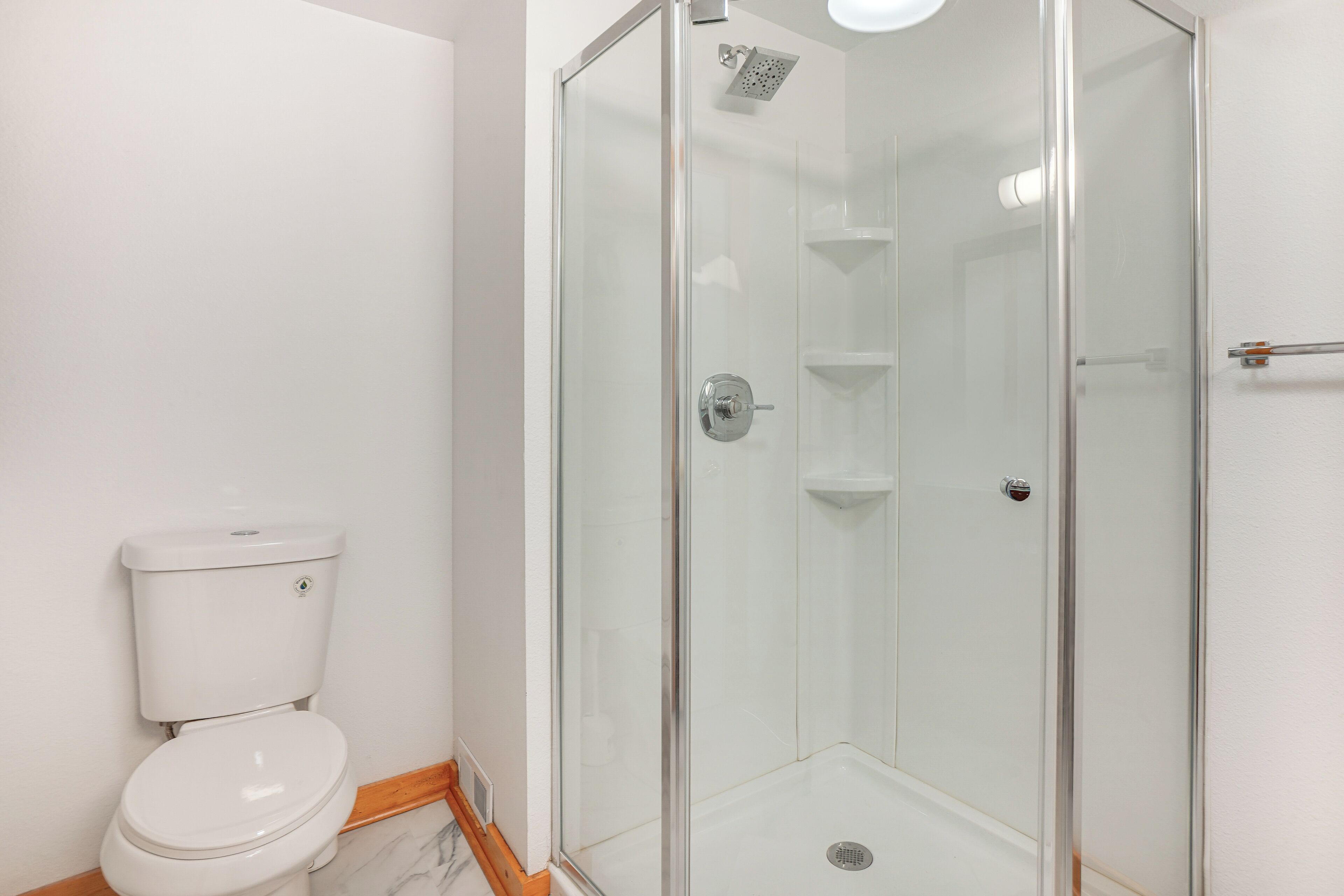 A bathroom with a toilet, a glass-enclosed shower, and a white sink.