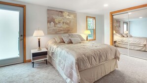 A bedroom with a large bed, bedside lamps, a mirror, and a painting on the wall. - 1 Mi to Shore: Lake Michigan Retreat w/ Game Room! (Two Rivers)