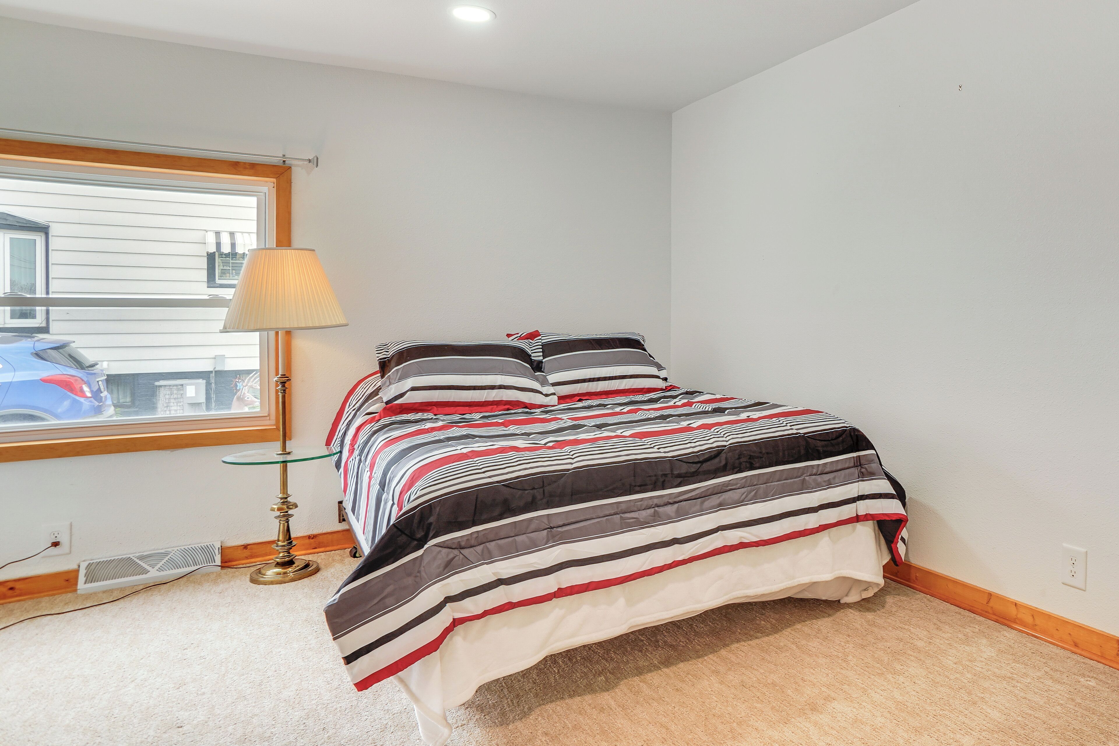 A bedroom with a bed, a lamp, and a window.