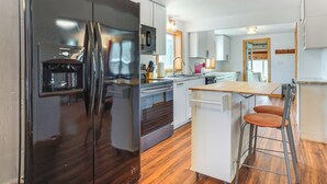A modern kitchen with a stainless steel refrigerator, a microwave, and a wooden countertop. - 1 Mi to Shore: Lake Michigan Retreat w/ Game Room! (Two Rivers)