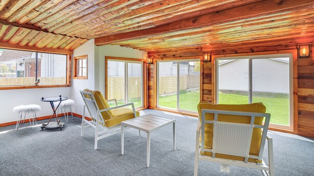 A room with a wooden ceiling, large windows, and a seating area with two chairs and a table. - 1 Mi to Shore: Lake Michigan Retreat w/ Game Room! (Two Rivers)