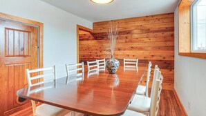 A dining area with a wooden table, white chairs, and a vase with branches. - 1 Mi to Shore: Lake Michigan Retreat w/ Game Room! (Two Rivers)