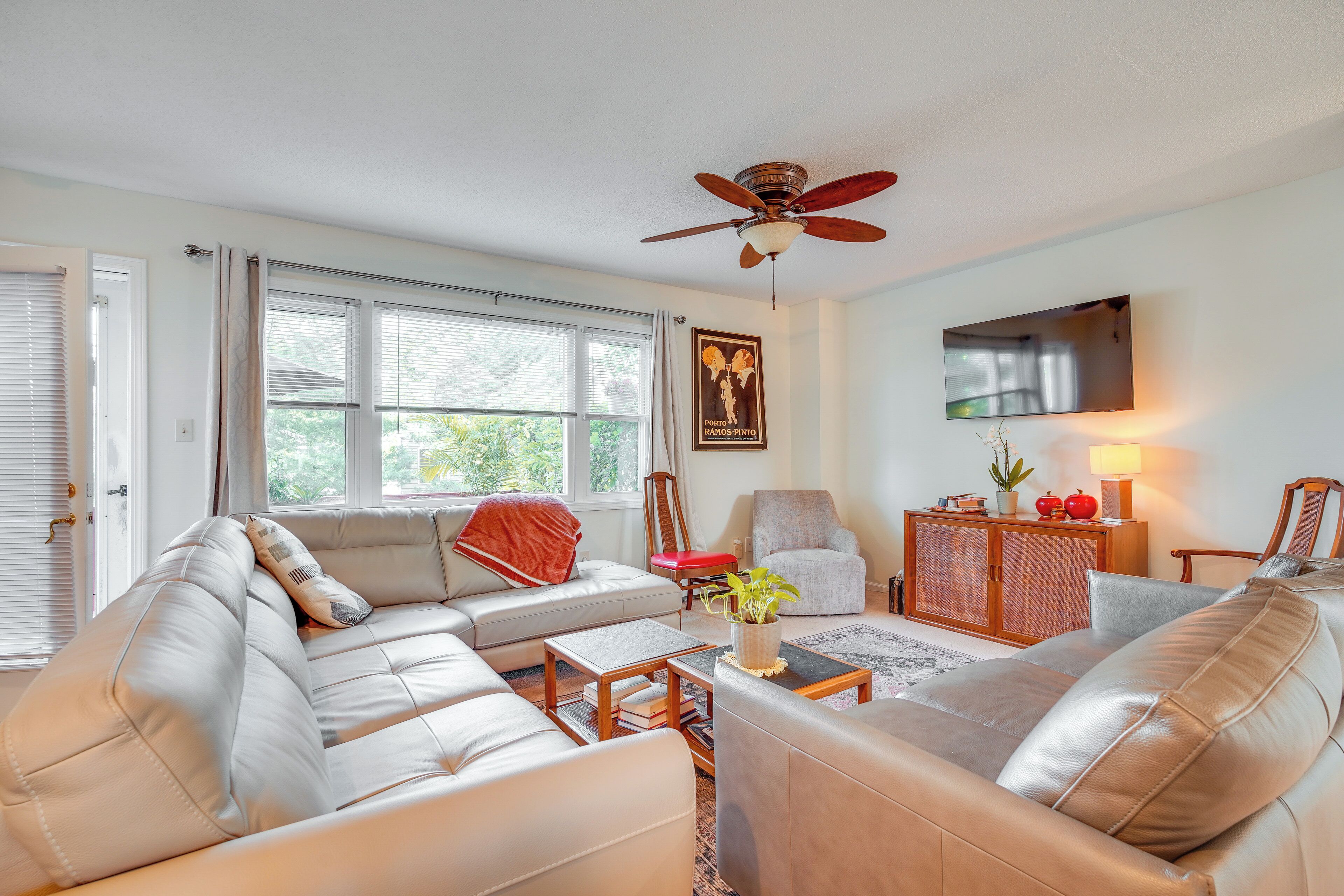 A living room with a sofa, armchairs, a coffee table, and a ceiling fan.