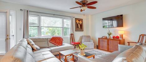 A living room with a sofa, armchairs, a coffee table, and a ceiling fan.