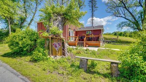 Een rode woning met een houten terras en een decoratie in de vorm van een hart.