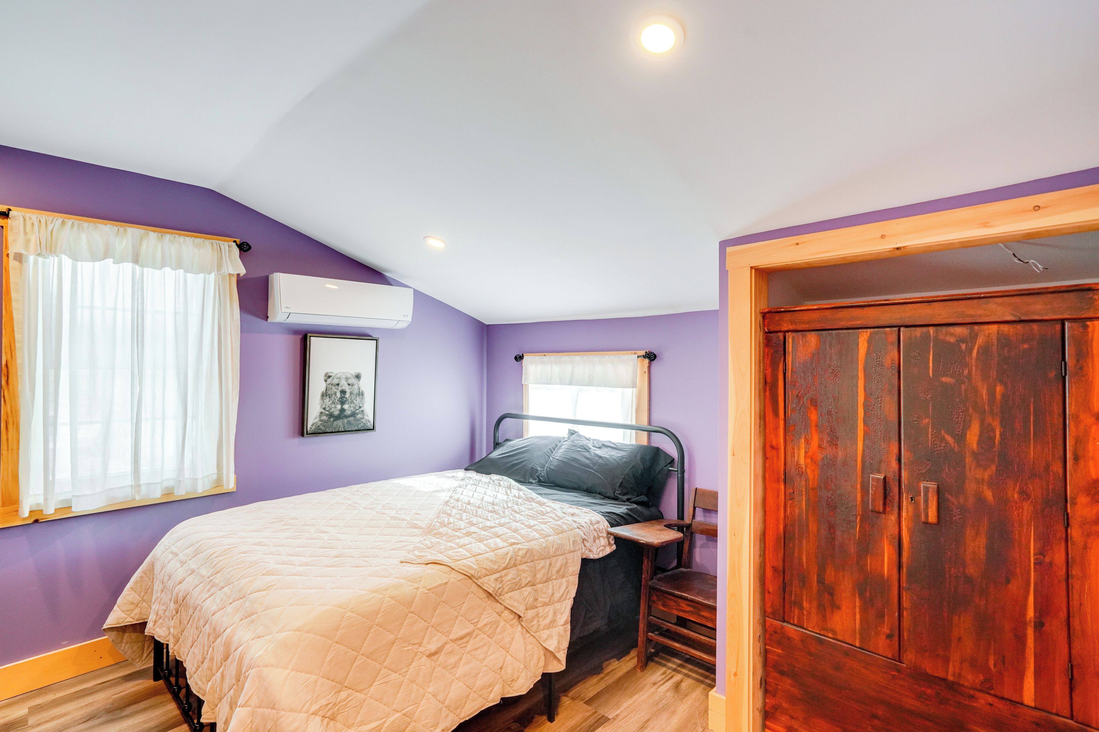 Une chambre à coucher avec un lit, une armoire et une fenêtre avec des rideaux.