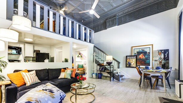 A spacious living area with a sofa, coffee table, and dining table. A staircase leads to an upper level. - 7 Mi to Dtwn: Charming Couple's Cove in Cincinnati (Cincinnati)