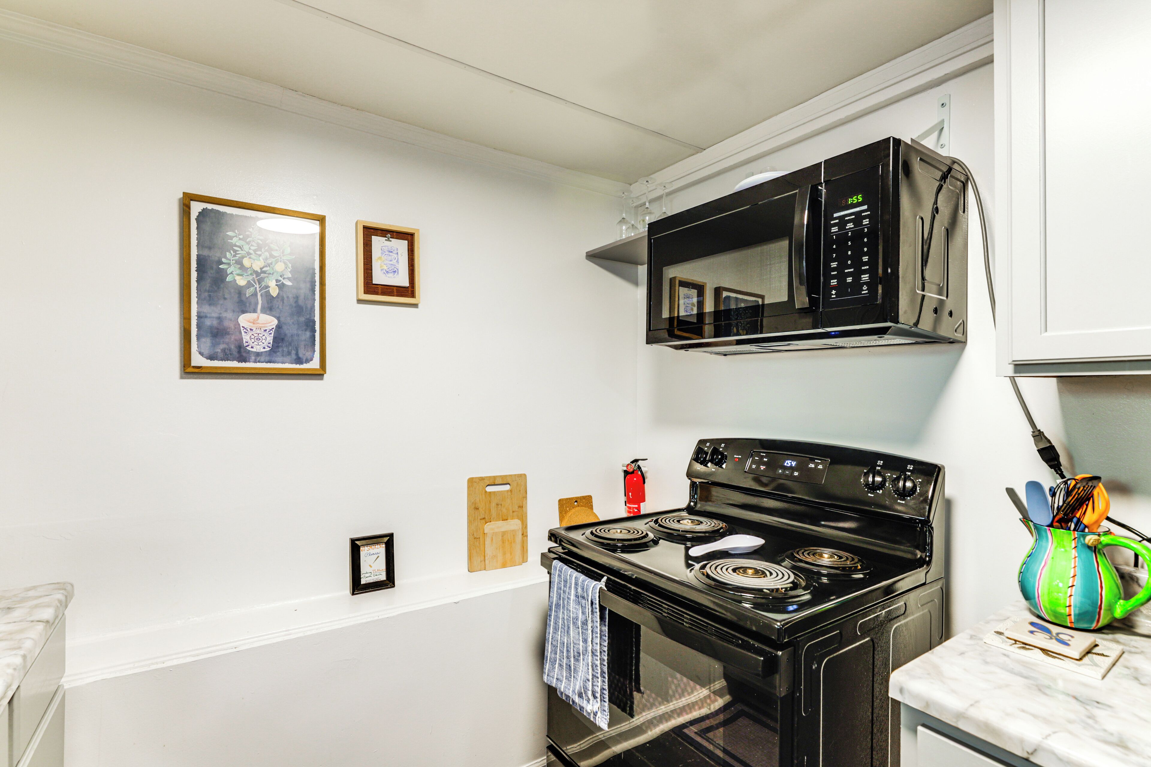 A kitchen with a stove, microwave, and a wooden cutting board on the wall.