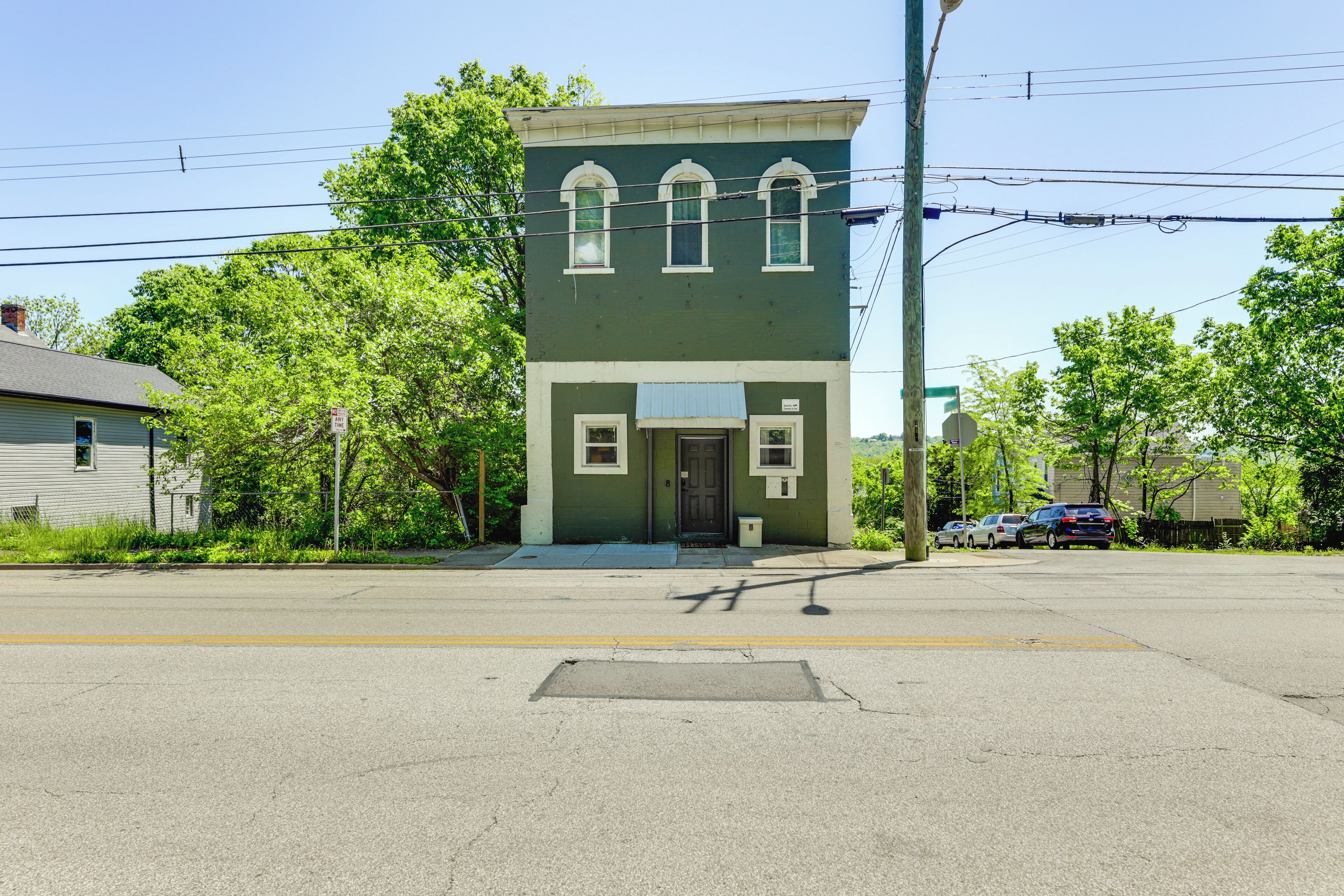 A two-story building with a green facade and white trim, featuring a front door and two windows on the ground floor.