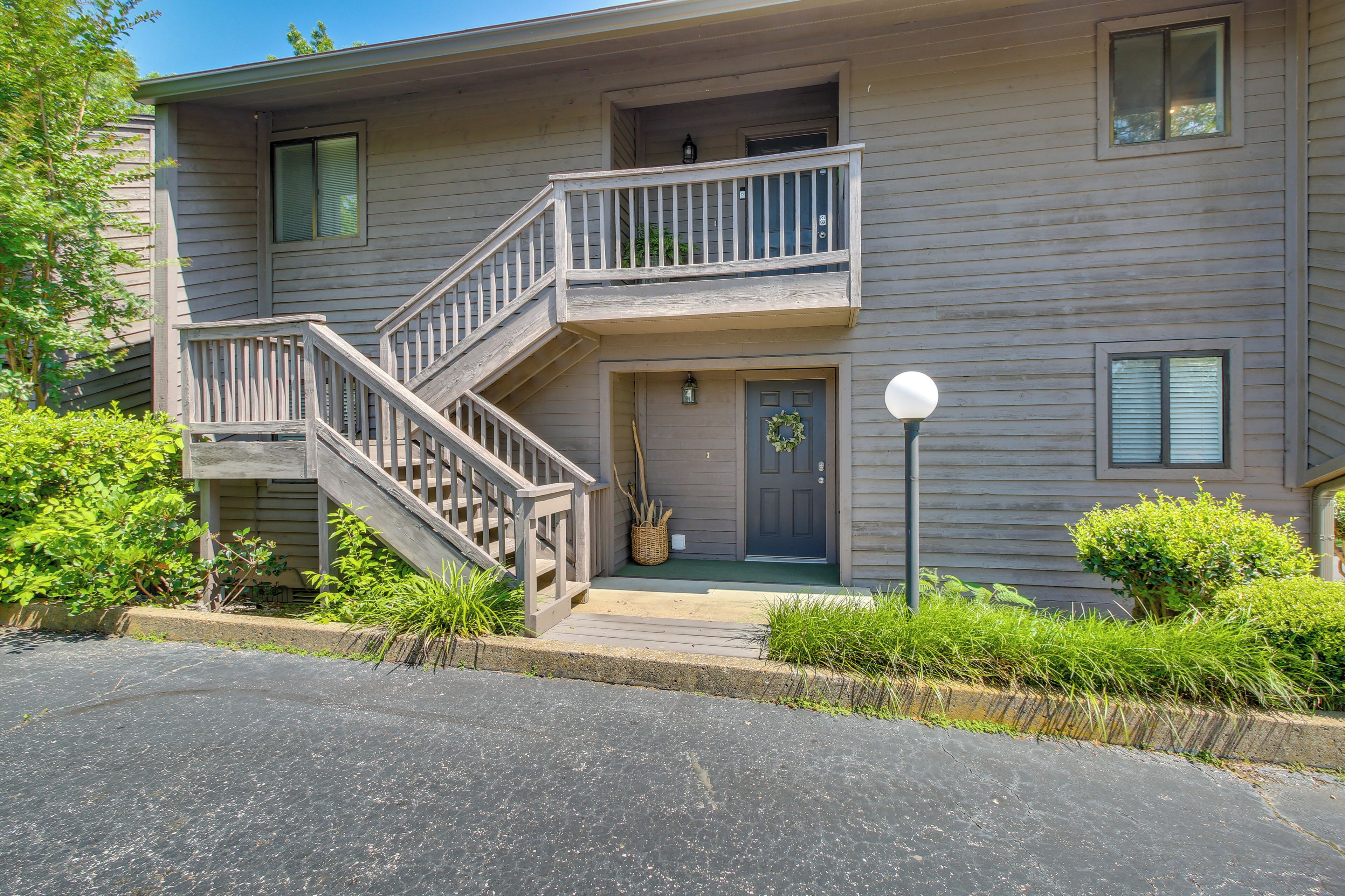 A two-story building with a wooden staircase, a front door with a wreath, and a small porch area.