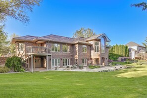 A two-story house with a balcony, a covered patio, and a well-maintained lawn.