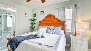 Une chambre avec un lit en bois, des tables de chevet blanches et une vue sur l’extérieur.