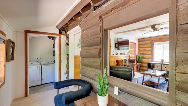 A room with a wooden ceiling, a sofa, a table, a potted plant, and a view of a kitchen and laundry area. - Hike, Bike & Explore: Woodsy Retreat in Mt Laguna! (Mount Laguna)
