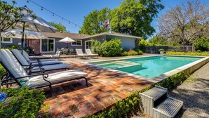 Un jardin avec une piscine, des chaises longues et un espace patio.