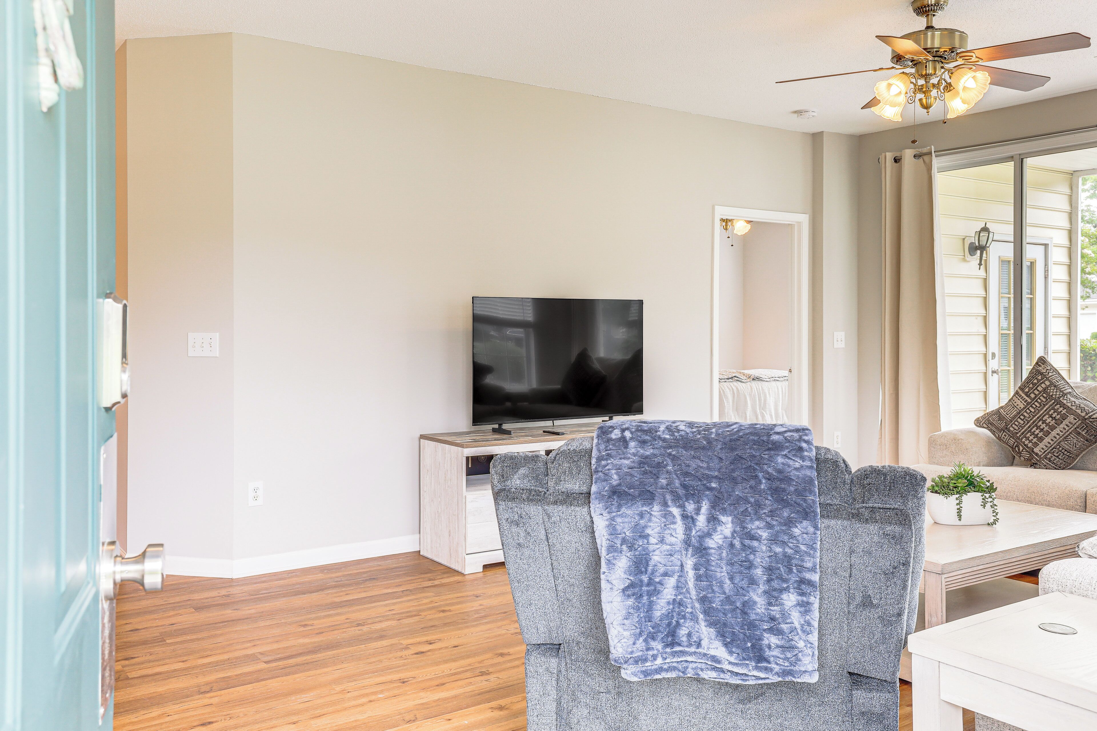 A living room with a TV, a ceiling fan, a sofa, and a coffee table.