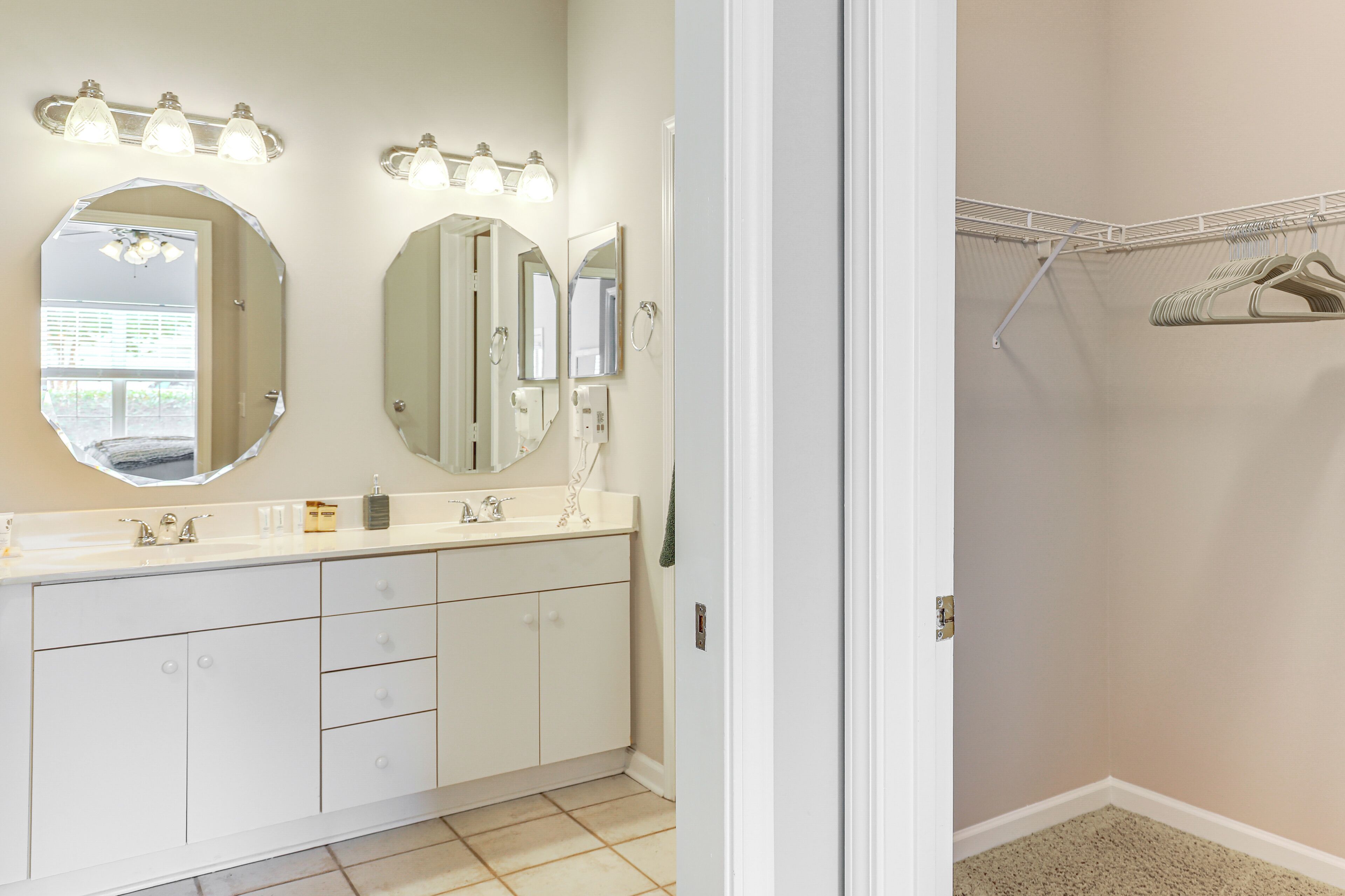 Une salle de bain avec un meuble-lavabo, deux grands miroirs et un espace coiffeuse éclairé.