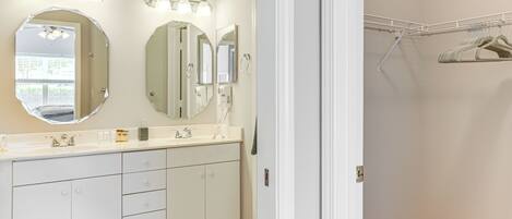 A bathroom with a vanity, two large mirrors, and a lighted vanity area.